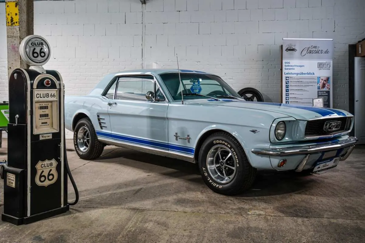 Ford Mustang im Showroom von OM-Classics neben einer historischen CLUB-66-Zapfsäule